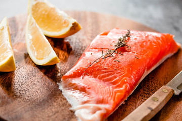 Raw salmon fillets pepper salt dill lemon and rosemary on a wooden board. Prepere for baking.