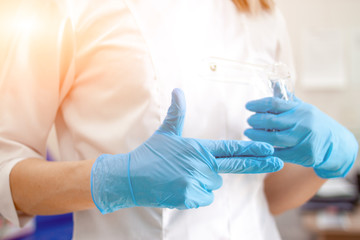 Wall Mural - Professional medical physician gynecologist doctor in white uniformin blue gloves makes gynecological finger sign. Cabinet with medical equipment on background. Woman health and pregnancy concept