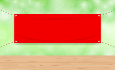Wall Mural - vinyl blank red on green bokeh background and wood plank table, mock up textile fabric empty for banner advertising stand hanging, indoor outdoor fabric vinyl backdrop for copy space presentation ad