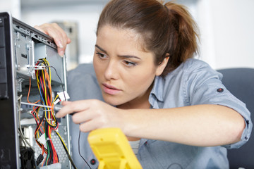 young female pc technician learning to fix a computer