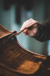 hands of artisan luthier varnishing, building a double bass