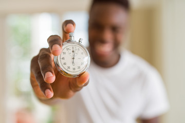 Wall Mural - Young african man holding silver retro stopwatch counting time