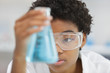© auremar - woman in glasses looks at the blue liquid in flask