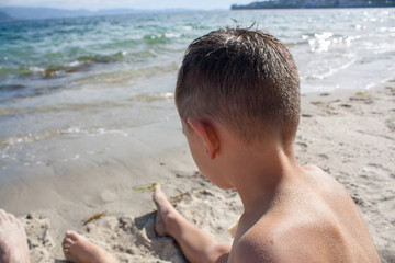 Young boy sat on the sand on a spanish beach