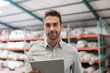 © mavoimages - Warehouse manager smiling while using a digital tablet