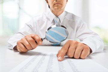 Canvas Print - Business analytics and statistics. Businessman with report using a magnifying glass.