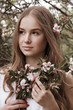 © Iveta - Beautiful young woman stay in apple blossom garden and keep a flowers bouquet u=in hers hands