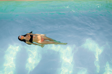 Wall Mural - Brunette caucasian model in  bikini floating in the pool water