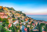 Fototapeta  - Aquamarine blue waters of  sea and fantastic cityscape of Taormina during sunset