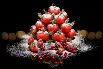 red tomatoes with berries simulate a christmas tree with bokeh lights