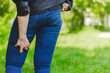 Young woman wearing jeans and leather jacket holding her painful upper leg while walking in nature – Girl massaging her inflamed and spasmed muscles