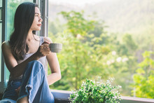 Beautiful Asian Woman Sitting Next To The Window Drinking Coffee And Relaxing With Beautiful Nature View 