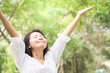 happy Asian woman arms up and breathing deep outdoors with nature background 