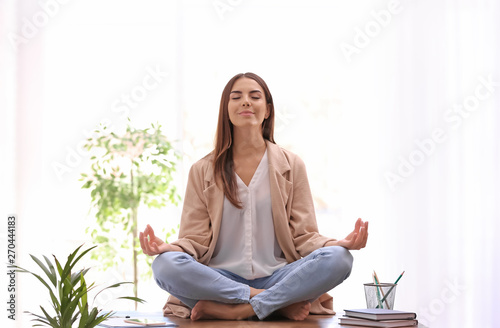 Fotomural Young businesswoman meditating at workplace. Zen concept