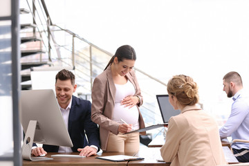 Poster - Young pregnant woman working with her employees in office