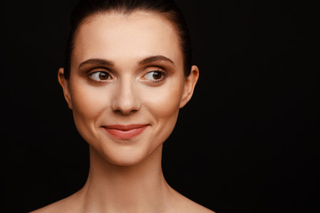 Wall Mural - Portrait of a beautiful woman with collected hair and bare shoulders on a black background