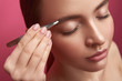 © Yakobchuk Olena - Beautician with elegant manicure plucking young lady eyebrows with tweezers