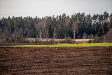 Sticker - cultivated fields in countryside with dark and wet soil for agriculture.