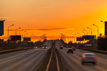 Symmetrical overpass extending beyond the horizon in the yellow orange light of the setting sun at the sunset. Nagaevskoe highway, Ufa, Bashkortostan, Russia - June 2015.