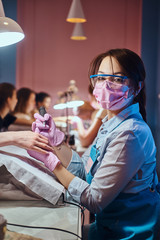 Wall Mural - Young cheerful manicure master at her own workplace with client is working on woman's nails.