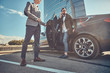 © Fxquadro - Handsome businessman in sunglasses is going out from car while his assistant is opening door for him.
