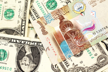 A colorful quarter dinar bank note from Kuwait close up in macro with American one dollar bills