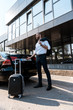 © LIGHTFIELD STUDIOS - low angle view of happy businessman standing near black car with luggage