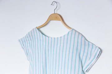 Wall Mural - A female blue stripe blouse with wooden hanger isolated white background.