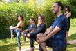 © Mangostar - Calm yogis working out in park. Men and women in fitness apparels standing on mats and stretching legs. Standing yoga pose concept