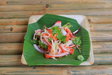 Canvas Print - Thai spicy seafood salad served on banana leaf on bamboo wooden table.