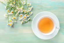A Cup Of Chamomile Tea, Shot From The Top On A Teal Blue Background With A Bouquet Of Flowers And A Place For Text