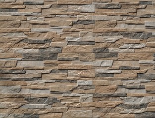 Stone wall cladding made of stripes artificial rocks. The colors are black,brown and gray Background, close up.