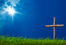 Close Up Wooden Cross On Green Grass Landscape Over Sunny Blue Sky