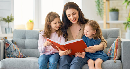 Wall Mural - mother reading a book to her daughters