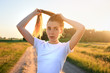 © Андрей Репетий - Young woman in a white t-shirt tying a tail during an evening jogging. Running concept for exercising, fitness and healthy lifestyle.