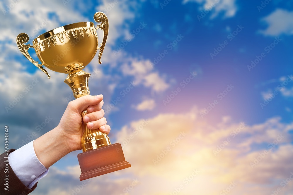 Hand holding golden trophy on background Stock Photo | Adobe Stock