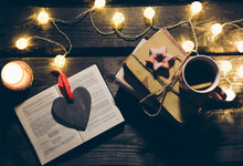 Holidays Mood Photo. Christmas Lights And Hot Tea Mug. Book For Cosy Evening. Sweet Gingerbread And Wooden Heart On Tray. Perfect Winter Flat Lay With Candle. Hygge Concept.