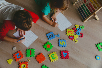 Wall Mural - little boy and girl learn to write and calculate numbers