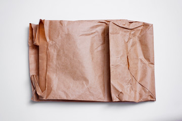 Wall Mural - Old empty brown craft package on white background. Delivery pouch. Crumpled paper texture.