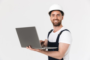 Confident bearded builder man wearing overalls standing