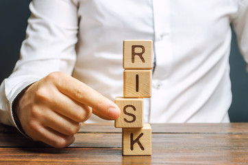 Man removes blocks with the word Risk. The concept of reducing possible risks. Insurance, stability support. Legal protection of business interests. Favorable investment climate. Financial pillow.