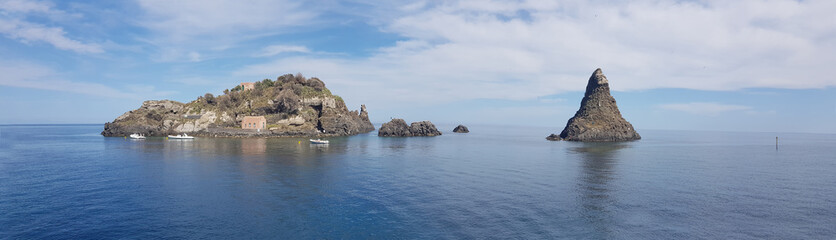 Aci Trezza panoramic view of cyclopean coastline, famous rocks and island in blue sea and sky of Sicily