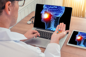 Wall Mural - Doctor or dentist holding pills with x-ray of 3D skull head with pain in the teeth on a laptop. Digital tablet on the wooden desk