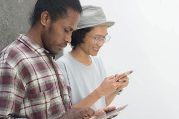 portrait of happy two man using smartphone, asian and black man best friend using smartphone and tablet