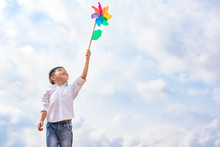 Boy Holding Colorful Pinwheel In Windy At Outdoors. Children Portrait And Kids Playing Theme.