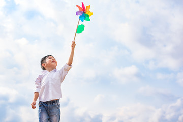 Boy holding colorful pinwheel in windy at outdoors. Children portrait and kids playing theme.