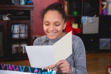 Portrait Of Smiling Happy Girl Reading A Birthday Card