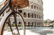 Close-up bike's wheel in front of colosseum in Rome at sunset.