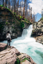 A Young Female Hiker In Glacier National Park Next To A Waterfall