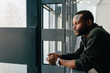 © MyMicrostock/Stocksy - Young black man with pensive expression looking out window